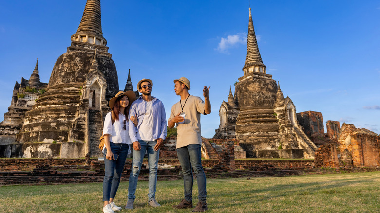 Un couple parle avec un guide près des stupas d'Asie du Sud-Est