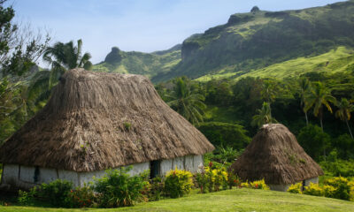 Le village fidjien éloigné entouré de montagnes luxuriantes et de huttes de chaume traditionnelles