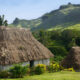 Le village fidjien éloigné entouré de montagnes luxuriantes et de huttes de chaume traditionnelles