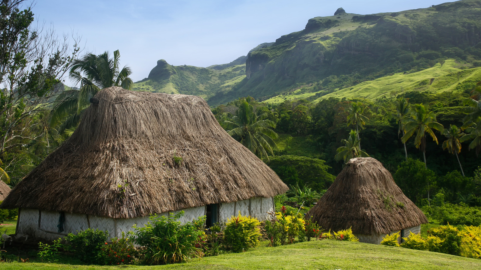 Le village fidjien éloigné entouré de montagnes luxuriantes et de huttes de chaume traditionnelles