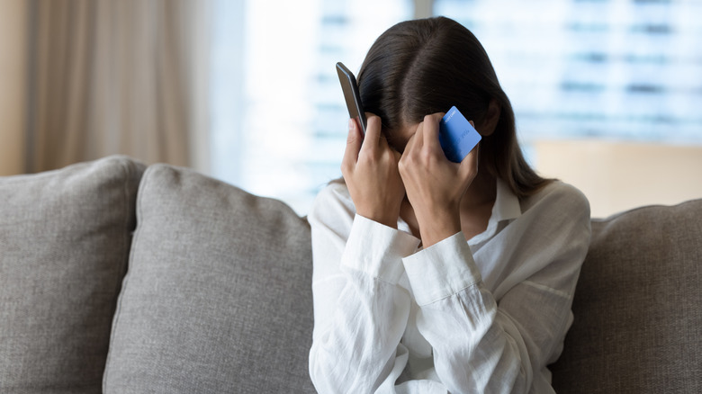 Femme frustrée en tenant son téléphone et sa carte de crédit