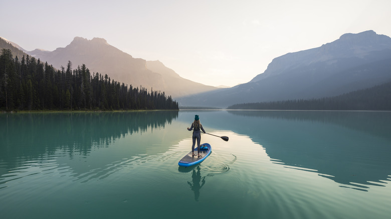 Femme sur le stand-up paddleboard sur le lac turquoise avec une toile de fond en arrière