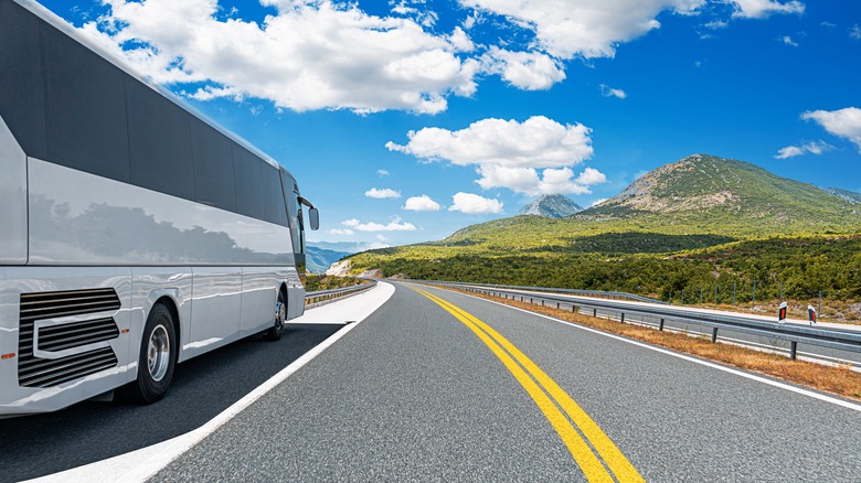 Un bus blanc navigue sur une route de montagne