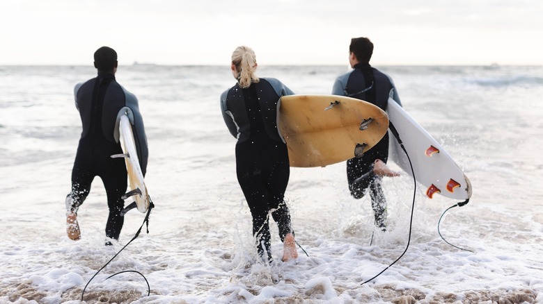 Groupe de surfeurs marchant dans l'eau