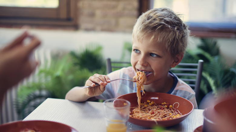 Jeune garçon mange des spaghettis