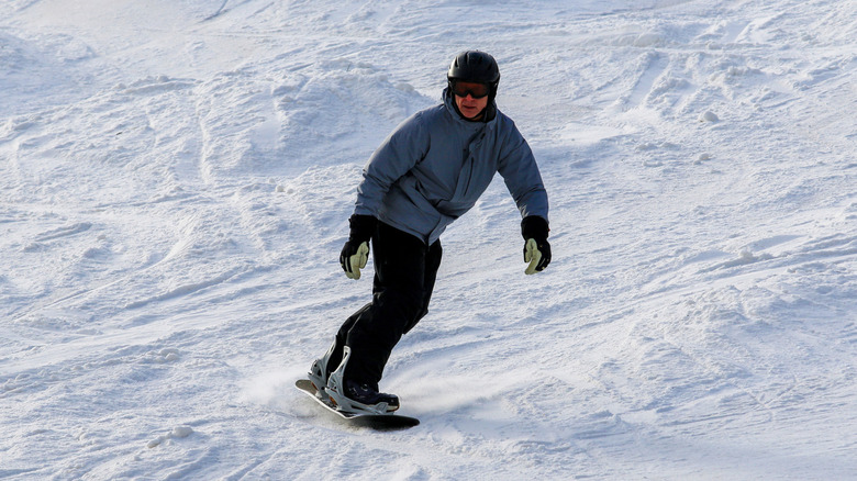 Un homme chevauche un snowboard sur une pente du Vermont