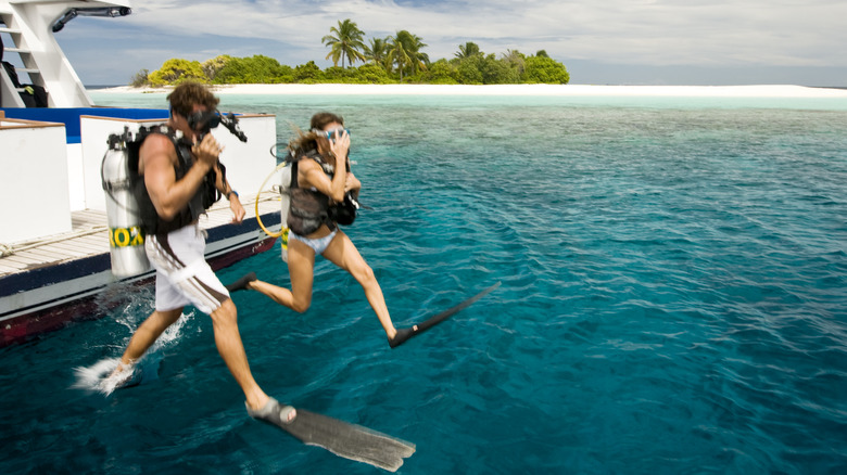 Couple sautant dans l'eau pour plonger aux Maldives