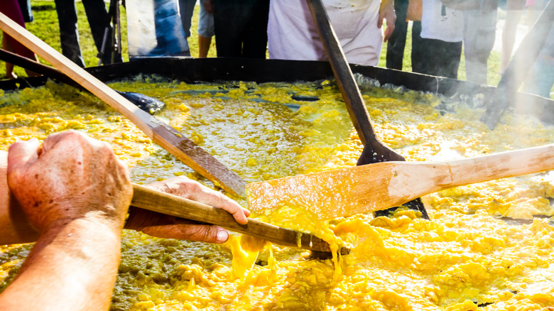 Hommes cuisinant une omelette géante dans une casserole