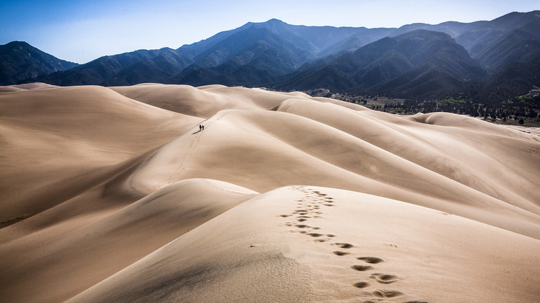 Randonneurs sur des dunes de sable du Colorado soutenues par des montagnes