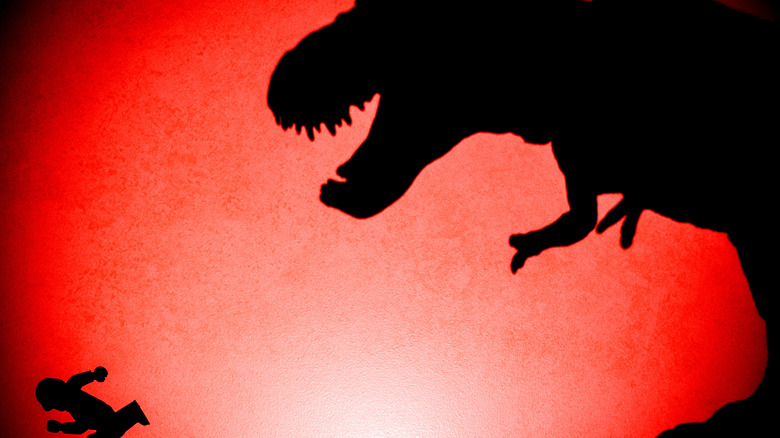 Silhouette de T-Rex chassant un humain