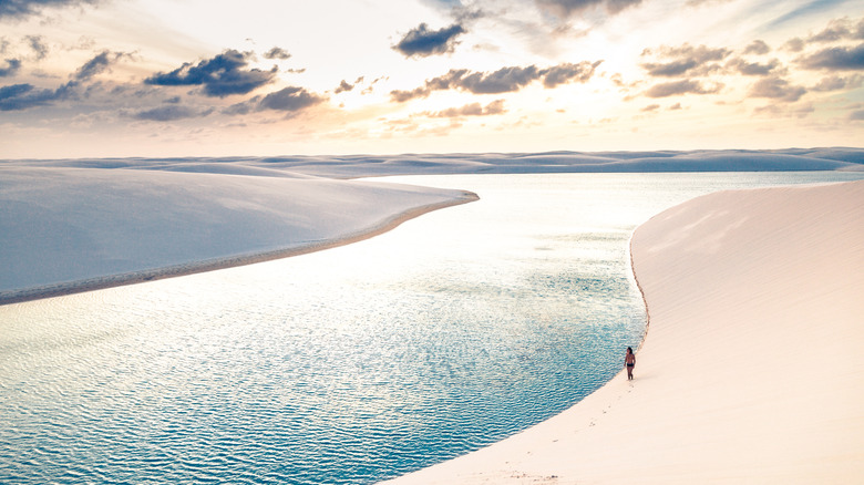 La personne marche le long des dunes près d'un lagon au parc national de Lençóis Maranhenses