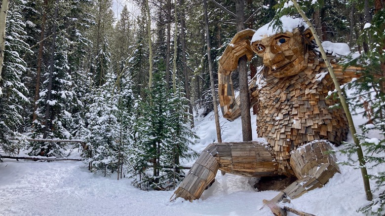 Une sculpture en bois d'un troll se trouve le long d'un sentier enneigé