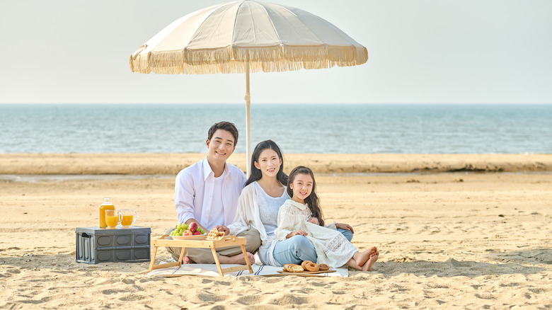 Une famille pose sous un parasol à franges sur la plage en Corée du Sud