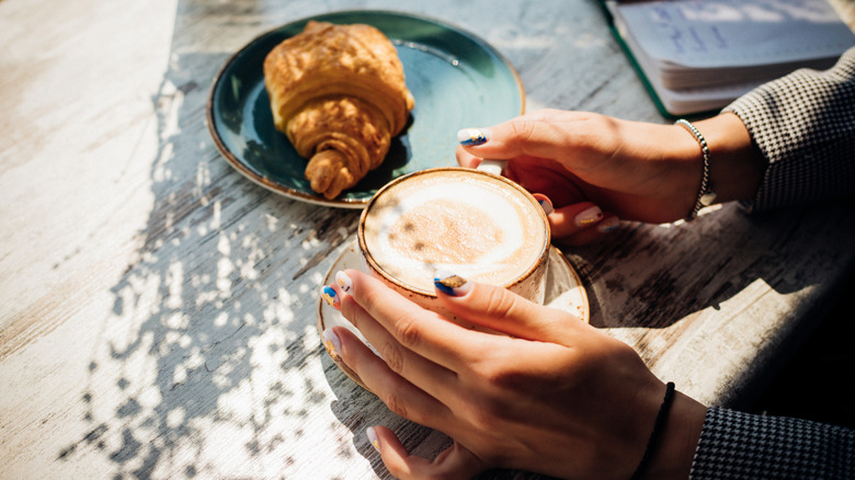 Tasse de café et croissant sur table ensoleillée