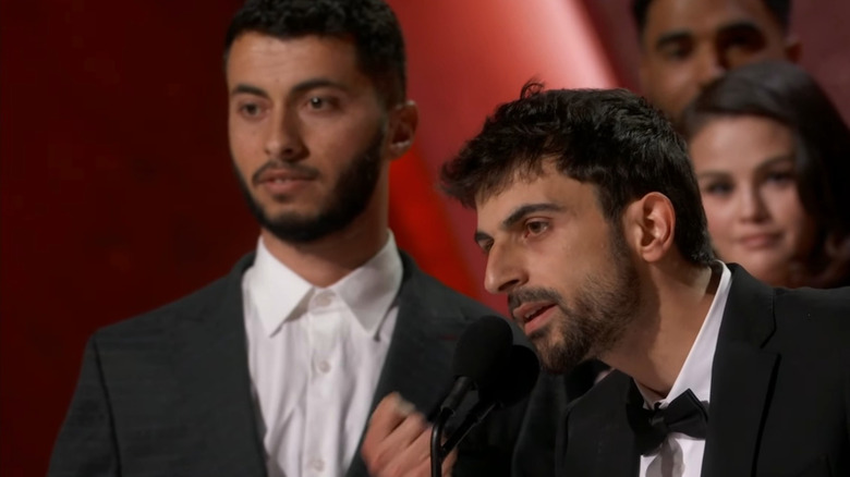 Yuval Abraham prononçant un discours aux Oscars alors que Basel Adra écoute en arrière-plan