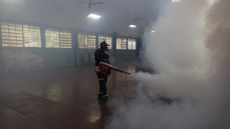 Un fumigateur pulvérise dans une grande pièce