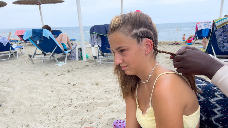 Jeune fille obtient des tresses sur la plage