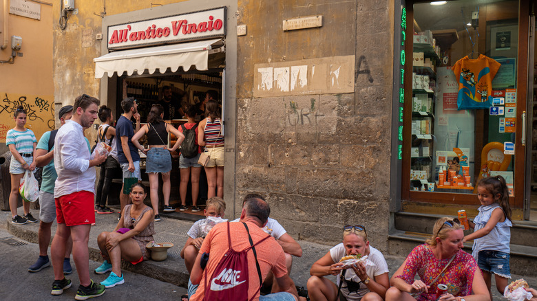 Une foule qui mange à l'extérieur de la boutique All'antico Vinaio Panini