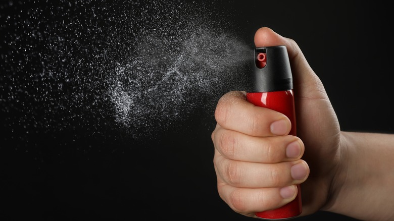 Personne activant le spray au poivre