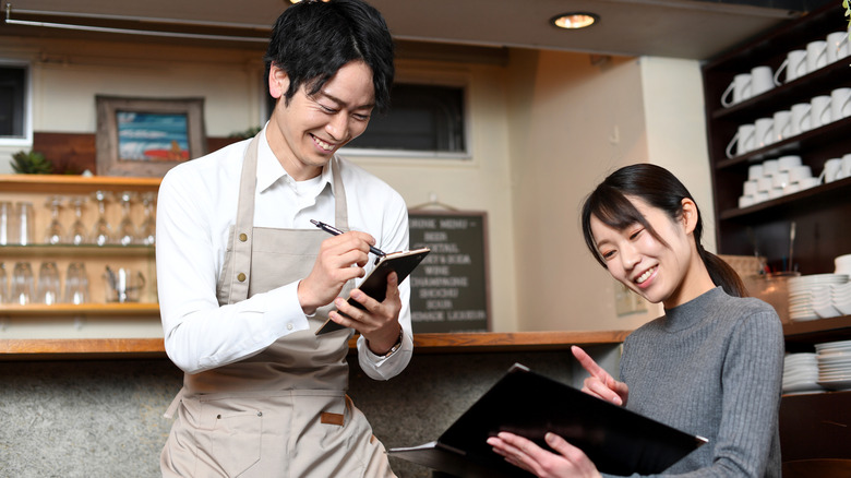 Une femme commande à un serveur dans un café