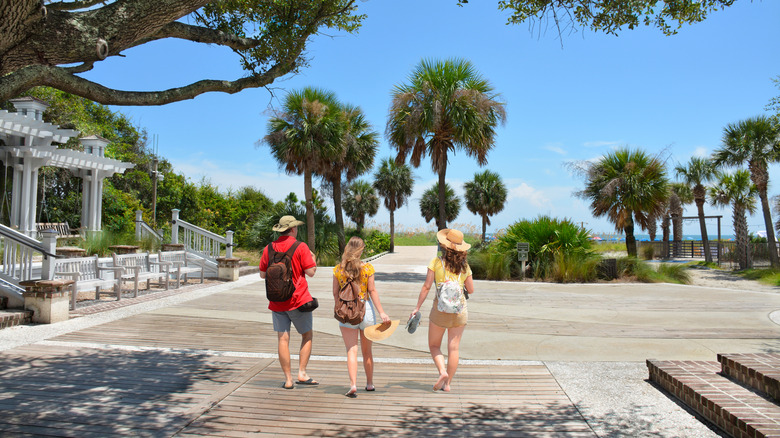 Trois personnes marchant sur la promenade en bois à Coligny Beach Park