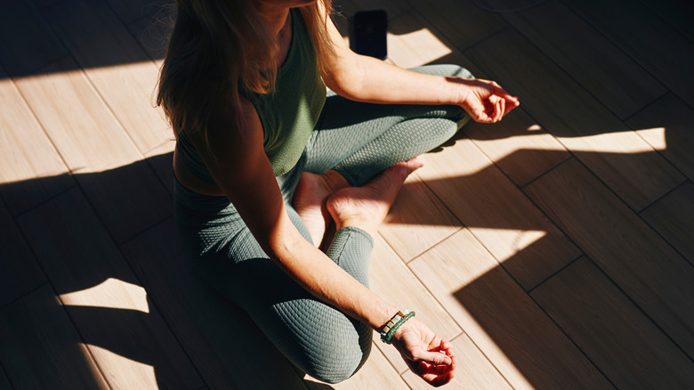 Une femme est assise sur un sol en méditant