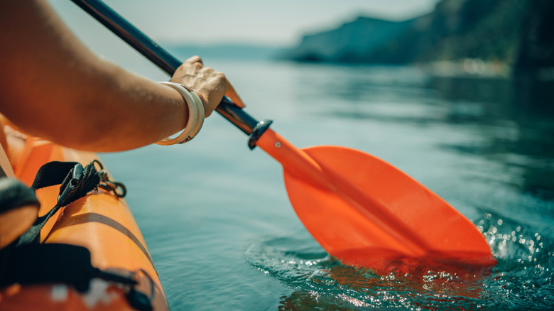 Un kayaker plonge propulse à travers le lac à l'aide d'une aviron d'orang