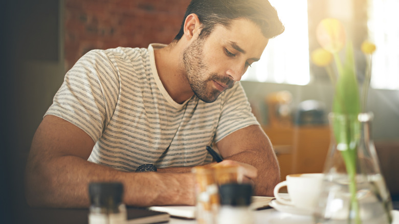 Un homme écrit dans son journal dans un restaurant