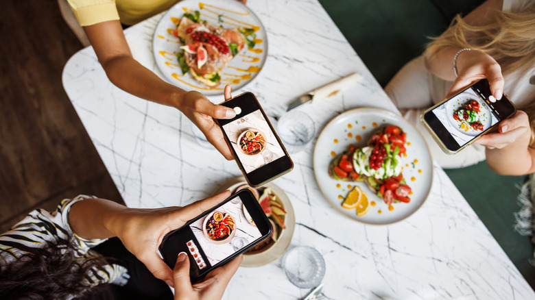 Les clients utilisent des téléphones pour photographier leurs repas dans un restaurant