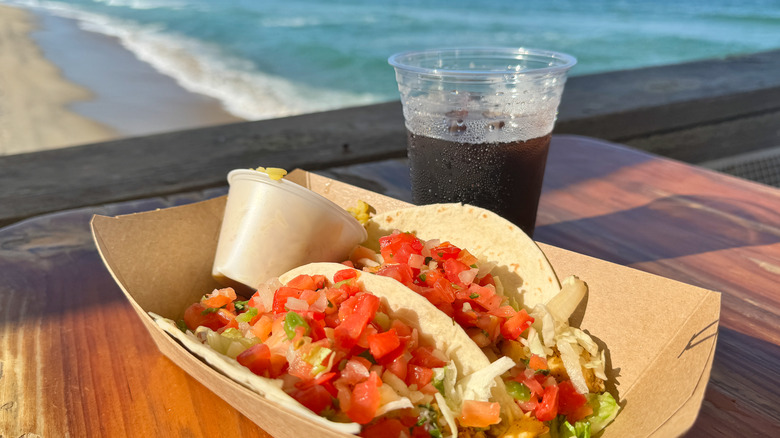 Fish Tacos et Cola sur table avec océan en arrière-plan