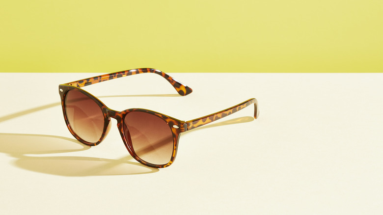 Les lunettes de soleil sont assises sur une table sur un fond jaune