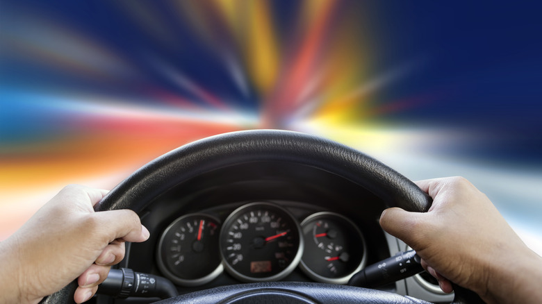 Mains sur un volant dans une voiture avec vue sur les lumières floues à travers le pare-brise