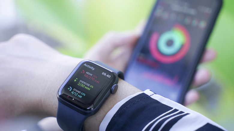 Une personne portant une montre Apple avec un iPhone en arrière-plan