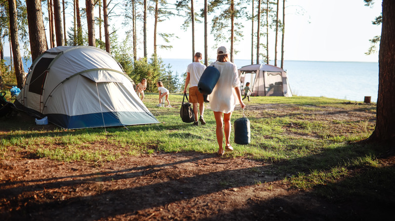Famille à la tente camping près des arbres et du lac