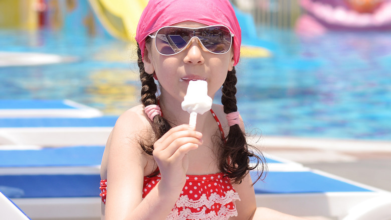 Enfant mangeant de la crème glacée au bord de la piscine