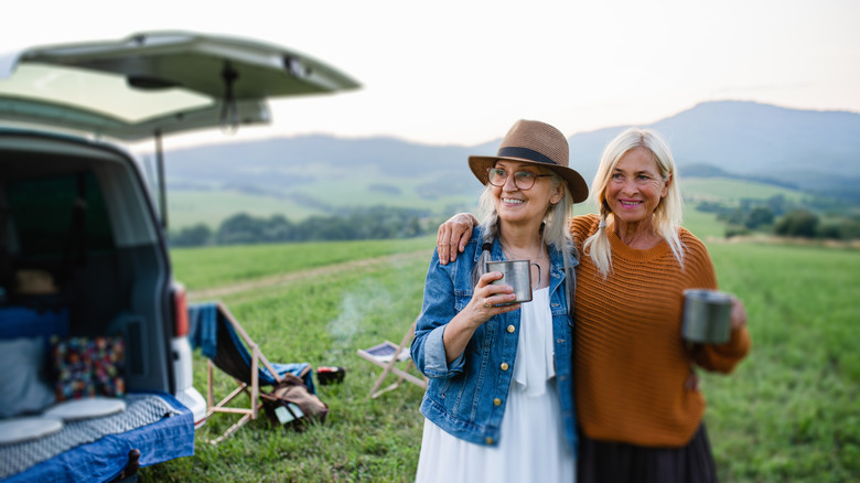 Deux femmes boivent de tasses devant un camping-car