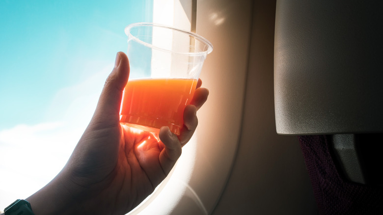 Voyageur d'avion tenant une tasse de jus