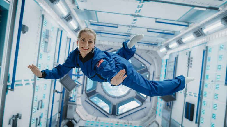 L'astronaute femelle flotte en zéro gravité dans l'espace