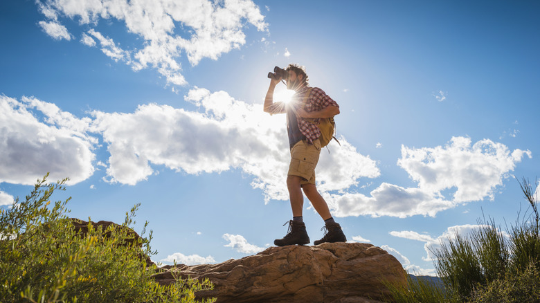 Un randonneur regarde à travers une paire de jumelles dans le désert