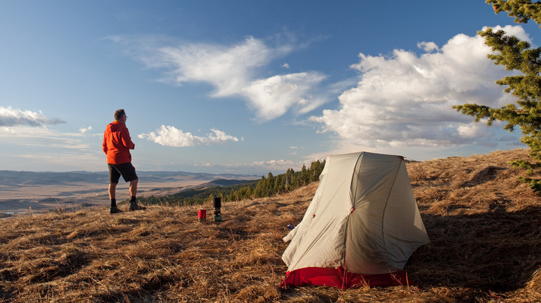 Un homme avec une tente solo campant dans une prairie
