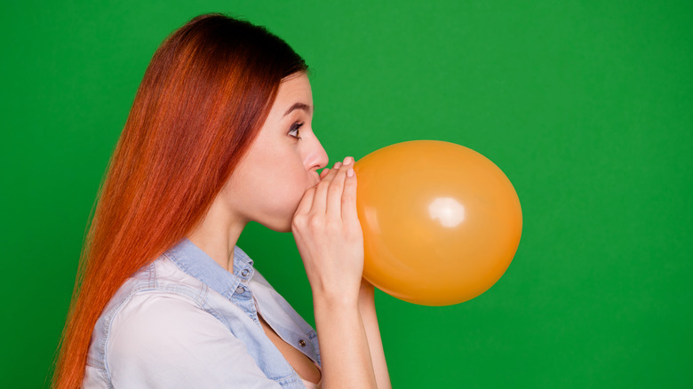 Femme rousse inhalant du ballon orange