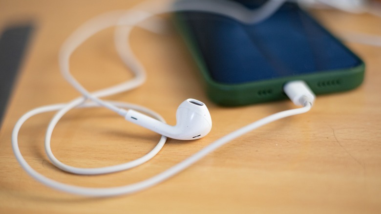 Apple Earpods connecté au port USB-C d'un smartphone conservé sur une table