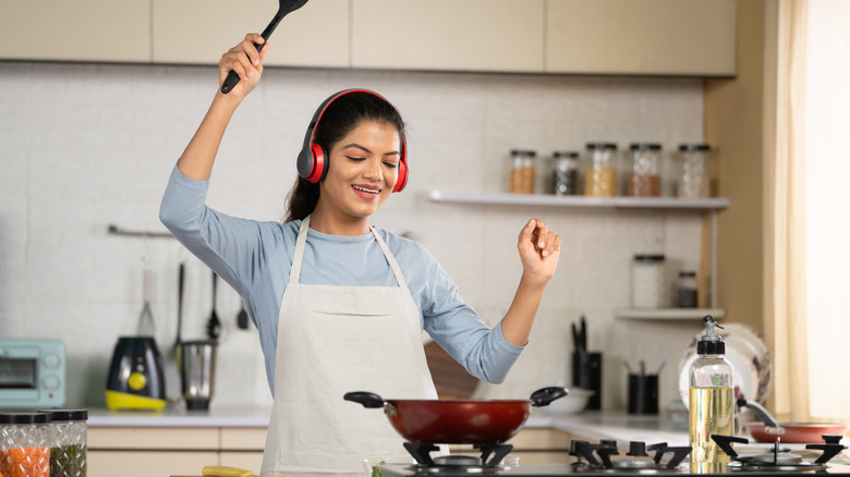 Une femme porte des écouteurs tout en préparant un repas dans la cuisine