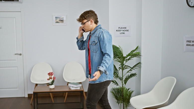 Un homme se promenant dans une salle d'attente tout en parlant au téléphone