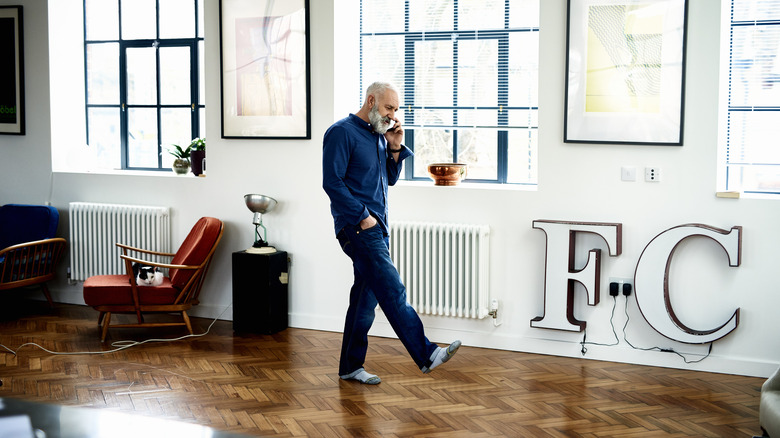Un homme fait des pas dans une pièce tout en parlant au téléphone