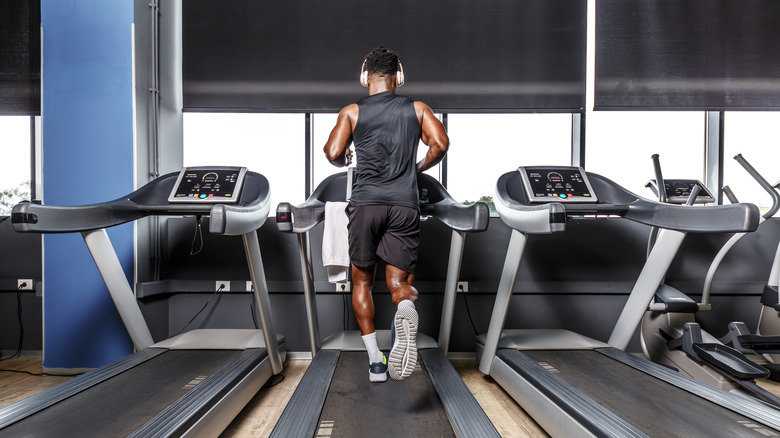 Un homme est vu derrière la course sur un tapis roulant dans une salle de sport