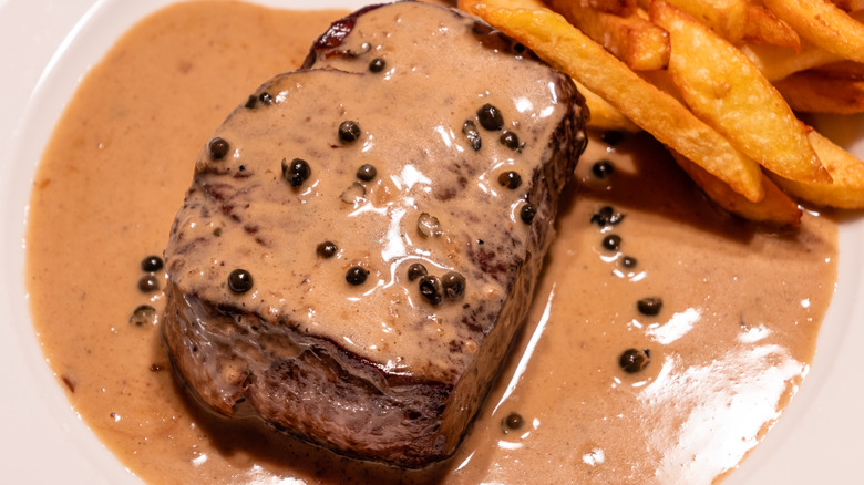 Steak au poivre sur une assiette avec des frites sur le côté
