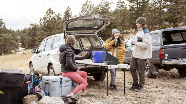 Les campeurs sont assis autour de la plate-forme de camping Hele Box transformée en table de camp