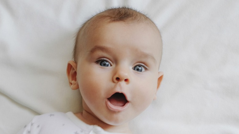 Bébé avec une expression surpris des yeux grands et de la bouche ouverte