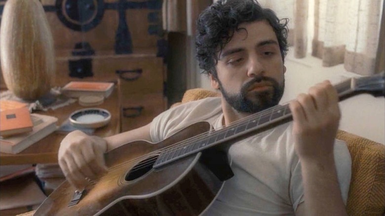 Oscar Isaac noue sur une guitare sous le nom de Llewyn Davis à l'intérieur de Llewyn Davis
